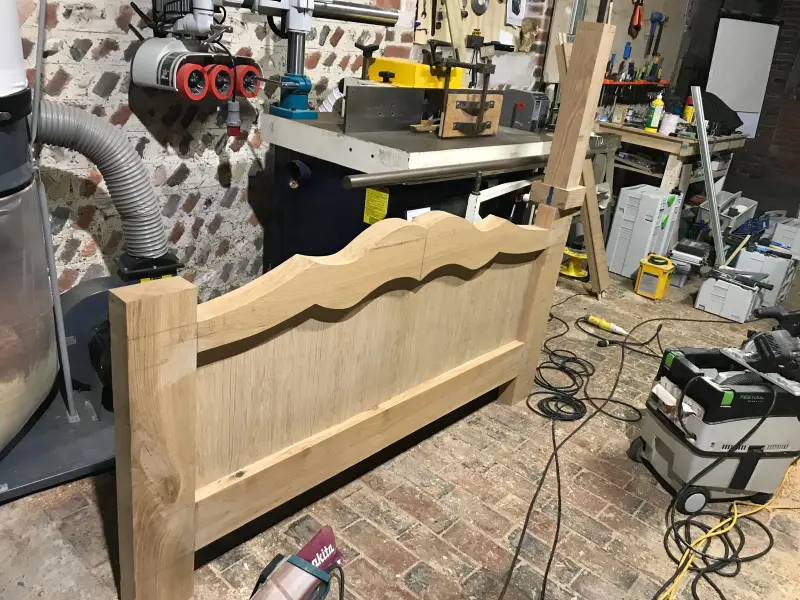 Oak bed frame with carved headboard in workshop